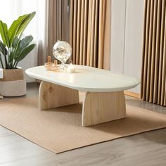 a white coffee table sitting on top of a rug next to a potted plant