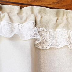 a close up of a white curtain with lace on the top and bottom part of it