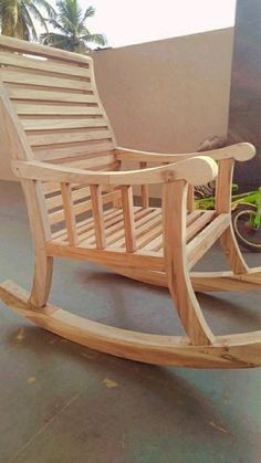 a wooden rocking chair sitting on top of a cement floor next to a green bike