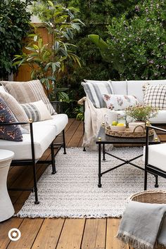 an outdoor living room with white furniture and plants