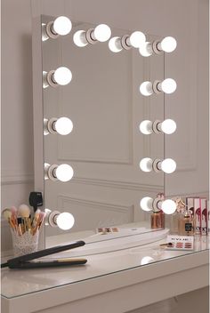 an image of a vanity mirror with lights and makeup brushes on it's side