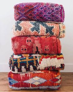 a stack of colorful rugs sitting on top of a wooden floor