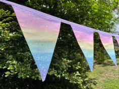 there is a purple and blue bunting banner on the grass near some green trees