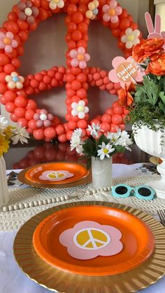 an orange plate with peace sign on it and flowers in vases next to the plates