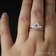 a woman's hand with an engagement ring on top of her finger and the other hand holding it