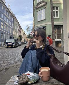 a woman sitting on a bench eating food and drinking coffee