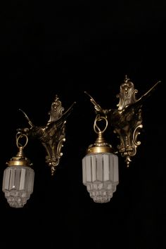 two antique style wall lights with glass shades on the top and one is gold plated