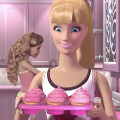 a barbie doll holding a tray with pink cupcakes on it in a kitchen