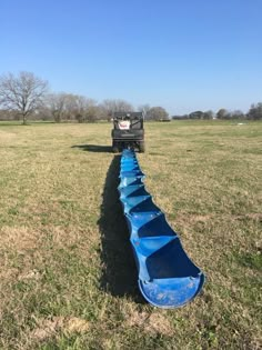 a long row of blue canoes sitting in the middle of a field next to a truck