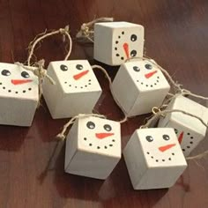 four snowmen made out of toilet paper sitting on a wooden table next to twine string