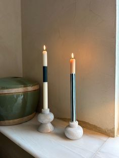 two candles sitting on top of a white mantle