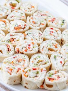 a white plate topped with rolls covered in veggie toppings on top of a table