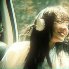 a woman wearing headphones sitting in the back seat of a car with long hair