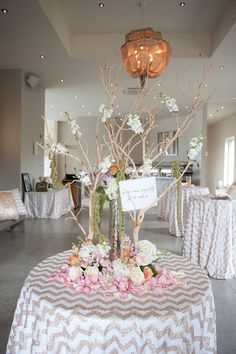 the table is decorated with white and pink flowers, branches, and signs for guests to sign