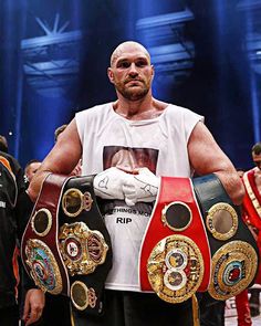 a man holding two boxing belts in his hands