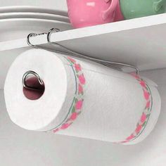 two rolls of toilet paper are hanging from the wall next to a shelf with plates and cups on it