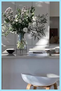 a vase filled with white flowers sitting on top of a counter next to a chair