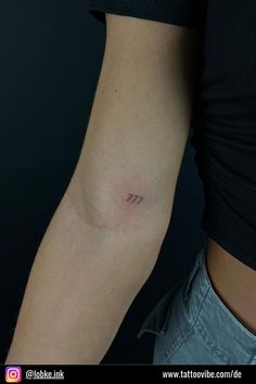 a woman's arm with a small arrow tattoo on the left side of her arm