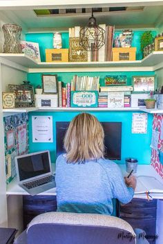 a woman sitting at a desk with a laptop computer in front of her and lots of books on the shelves behind her