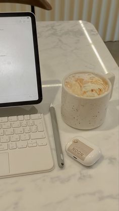 an open laptop computer sitting on top of a white table next to a cup of coffee