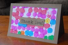 a handmade thank you card with colorful circles on it and a paper tag attached to the front