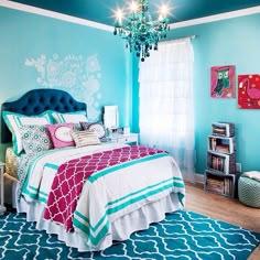 a bedroom decorated in blue and pink with a chandelier hanging from the ceiling