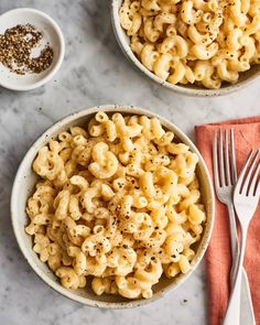 two bowls filled with macaroni and cheese on top of a marble countertop