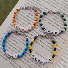 three bracelets with name charms on them sitting on top of an open book,