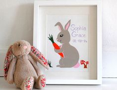 a stuffed rabbit sitting next to a framed print