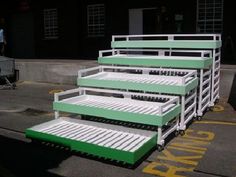 three green and white bunk beds sitting on the side of a road in front of a building