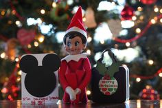 an elf is sitting next to a mickey mouse ornament