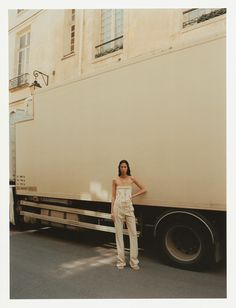 a woman standing in front of a truck on the road with her hands on her hips