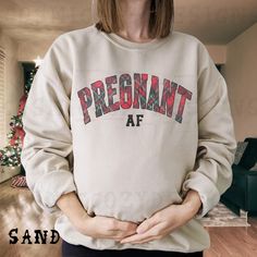 Celebrate the holiday season with a touch of humor and style with our Christmas Maternity Sweatshirt. This festive sweatshirt is perfect for merry and pregnant moms, making it an ideal expecting mom gift. Featuring a fun "Pregnant AF" design, this Santa baby crewneck is a witty pregnancy announcement shirt that will have you bumpin' around the Christmas tree in cozy Xmas sweater style. Treat yourself or gift it to an expecting mom for a delightful and funny holiday shirt that brings joy and laughter to the season. PRODUCT INFO ~ Gildan 18000 Crewneck Sweatshirt ~ 50% Cotton 50% Polyester (Heather colors are 60/40) ~ Printed using Direct To Garment style- Inks are printed directly into the fabric. ~ Colors may differ slightly due to different user monitor and screen settings. SIZE GUIDE ~ S Maternity Sweatshirt, Christmas Maternity, Funny Holiday Shirts, Christmas Pregnancy, Pregnancy Announcement Shirt, Funny Holiday, Xmas Sweater, Brings Joy, Sweater Style