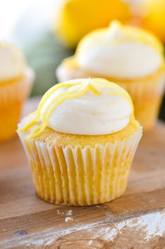 three cupcakes with white frosting are lined up in a row on a plate