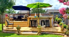 an outdoor kitchen and dining area with umbrellas in the back yard on a sunny day