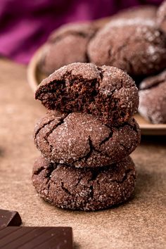 three chocolate cookies stacked on top of each other next to a plate of chocolate chips