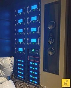 a room that has some speakers on the wall and a couch in front of it