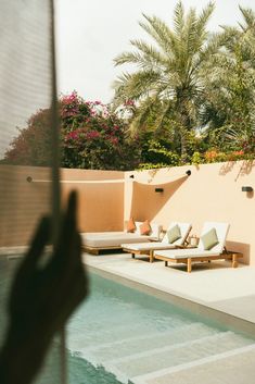 two lounge chairs sitting next to a swimming pool