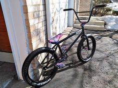 a black and pink bike parked in front of a building with snow on the ground