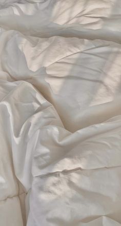 an unmade bed with white sheets and pillows