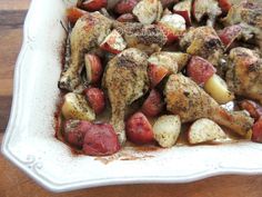 chicken and potatoes in a white dish on a wooden table