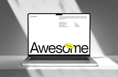 an open laptop computer sitting on top of a white table with the word awesome written on it