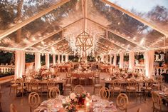 a large tent with tables and chairs set up for an outdoor wedding reception at night