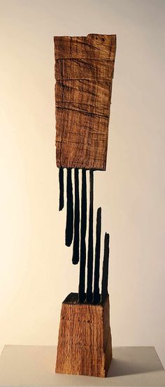 a piece of art made out of wood with black sticks sticking out of it's sides