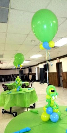 some green and blue balloons sitting on top of tables