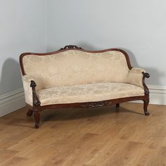 an old style couch sitting on top of a hard wood floor next to a wall