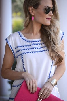 The Georgina Top - Breezy white blouse with blue embroidery. Looks great with bold warm colored accessories like this hot pink clutch! Top- $59.00 Chic Embroidered Top For Spring Brunch, Chic Embroidered Tops For Vacation, Chic Blue Tops With Floral Embroidery, Spring Vacation Blouse With Embroidered Hem, Spring Vacation Embroidered Neckline Top, Spring Vacation Embroidered Top With Embroidered Neckline, Chic Embroidered Beach Tops, Chic Spring Vacation Embroidered Top, Spring Blue Geometric Embroidered Blouse