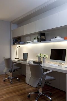 a desk with two chairs and a computer on it in an office space that is well lit