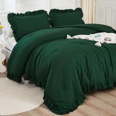 a green comforter with ruffled edges on a white rug in front of a bed