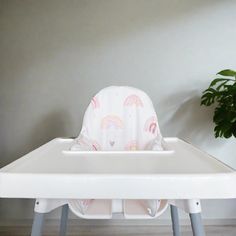 a baby's high chair with a seat cover on it and a potted plant in the background